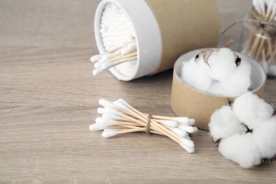 Photo of Cotton swabs and flowers on wooden table. Space for text