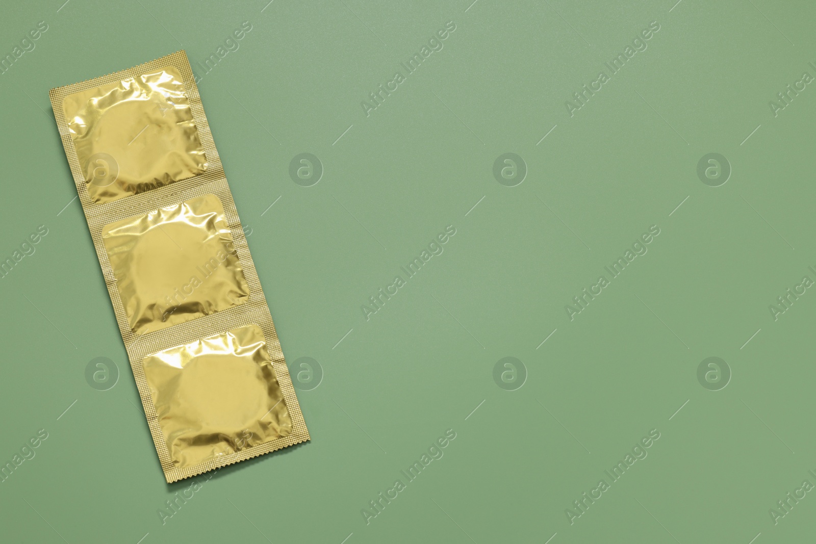 Photo of Packaged condoms on light green background, top view with space for text. Safe sex