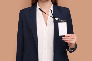 Photo of Woman with blank badge on light brown background, closeup