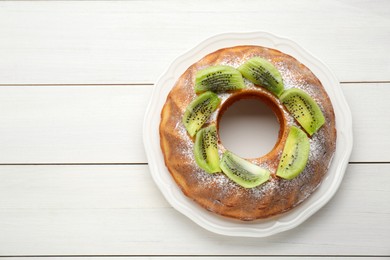 Photo of Homemade yogurt cake with kiwi and powdered sugar on white wooden table, top view. Space for text
