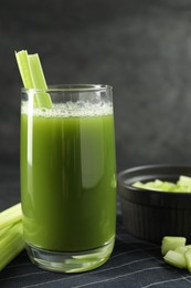 Glass of delicious celery juice and vegetables on table, closeup
