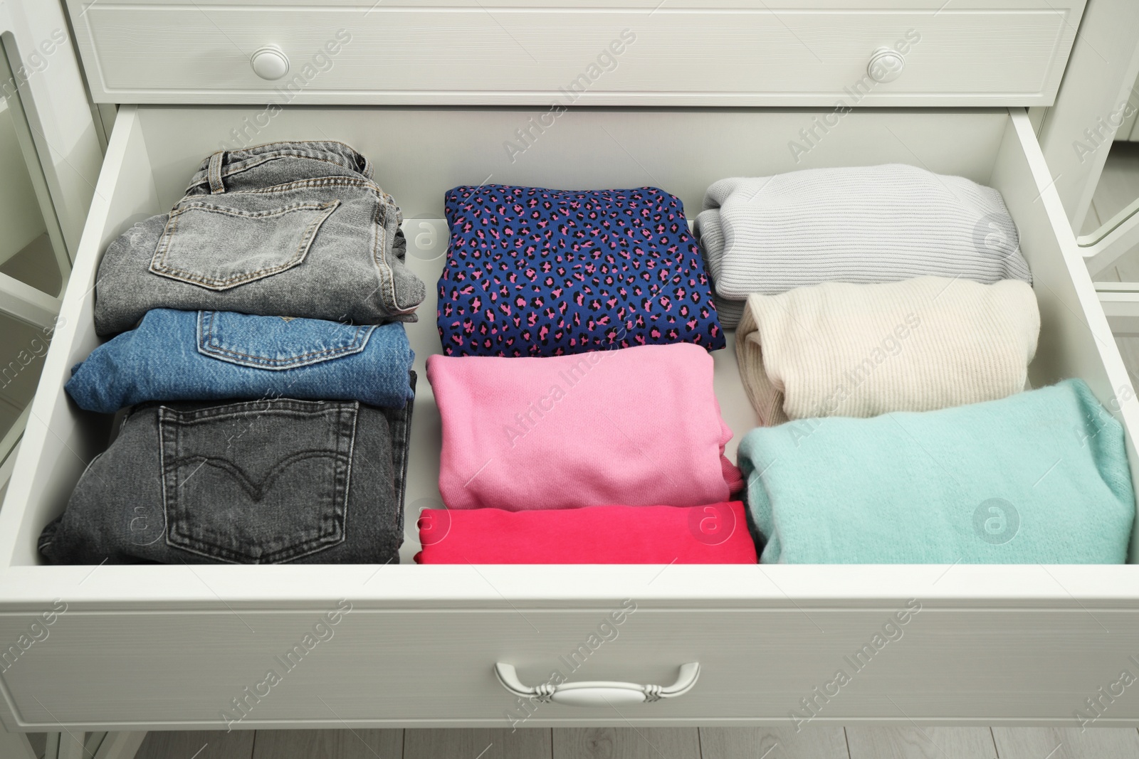 Photo of Folded clothes in open drawer. Apparel storage