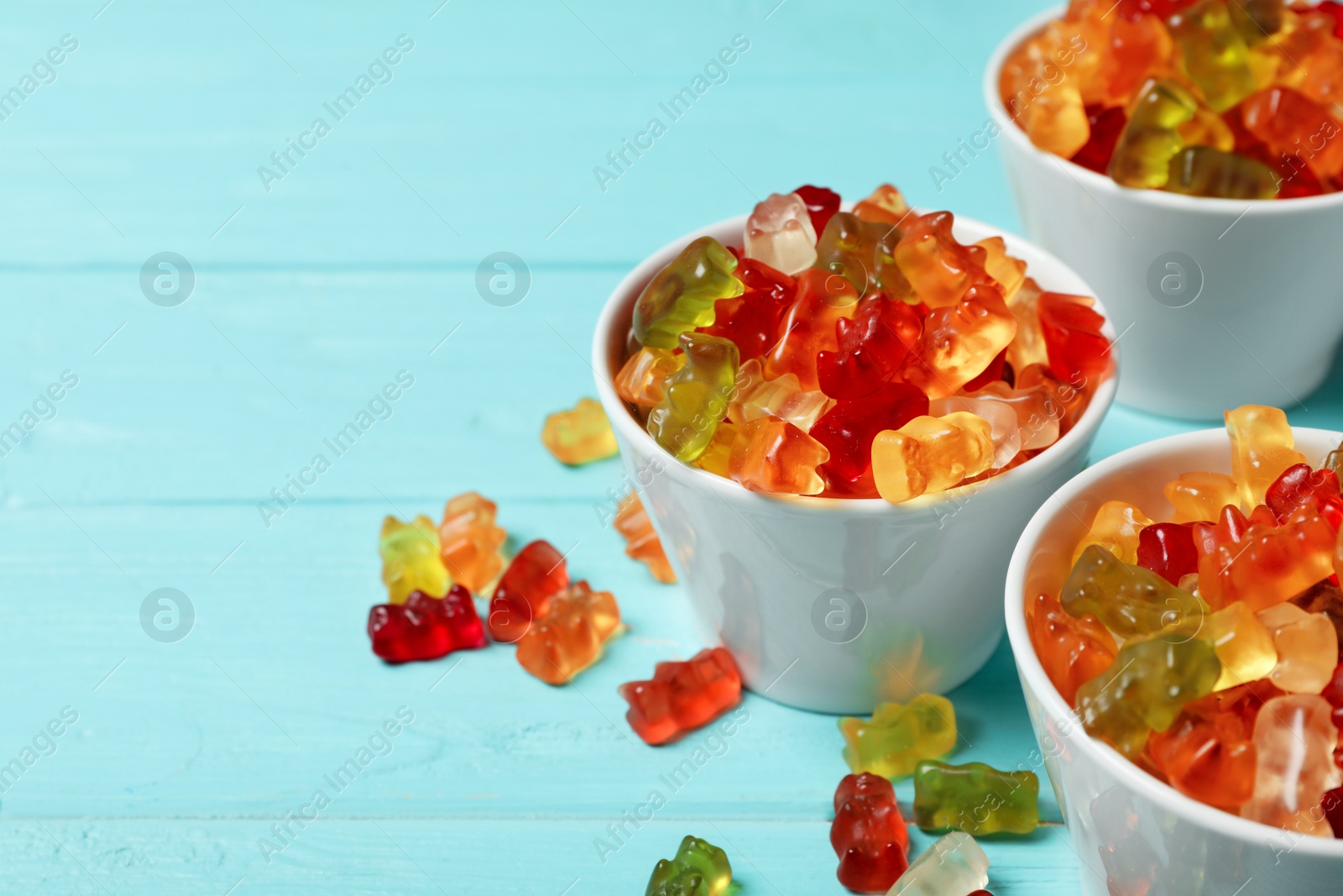 Photo of Bowls with delicious jelly bears on wooden table. Space for text