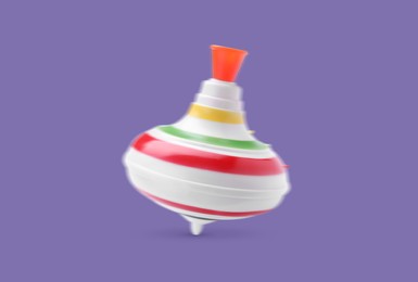 One spinning top in motion on purple background. Toy whirligig