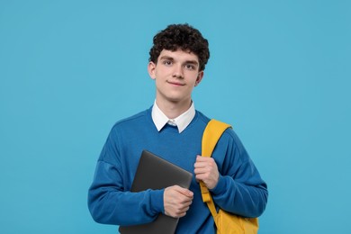 Photo of Portrait of student with backpack and laptop on light blue background
