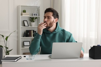 Photo of Man using cigarette holder for smoking at workplace in office