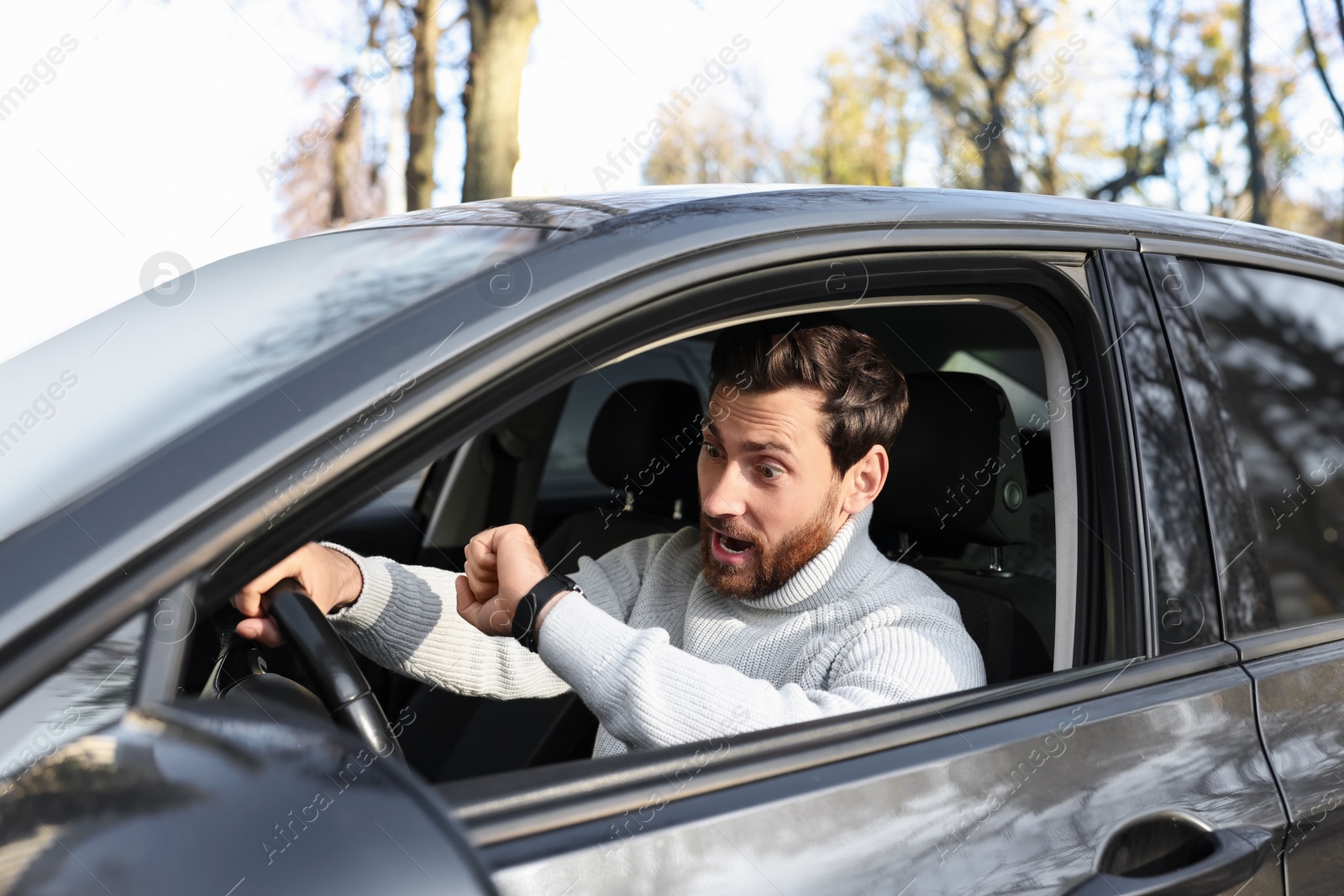 Photo of Emotional man checking time on watch in car. Being late concept