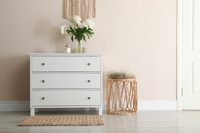 Photo of Room interior with white chest of drawers near beige wall. Space for text