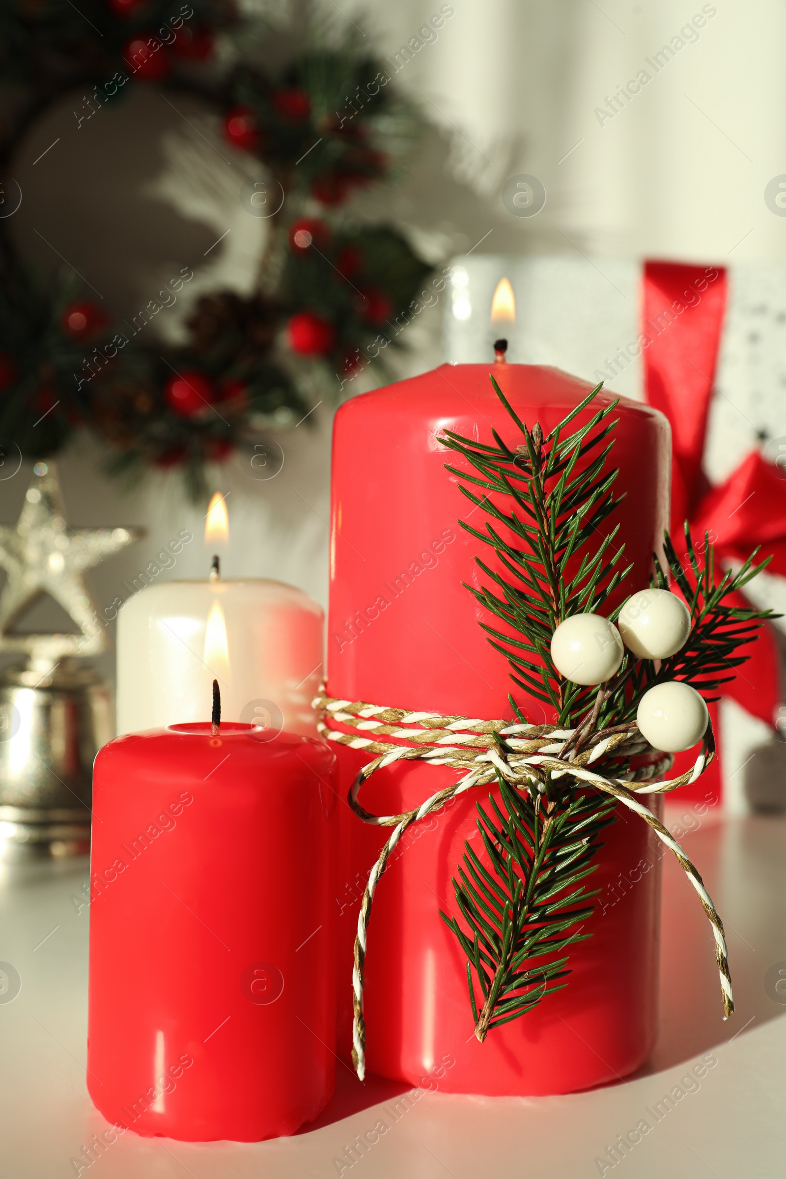 Photo of Burning candles with Christmas decor on white table