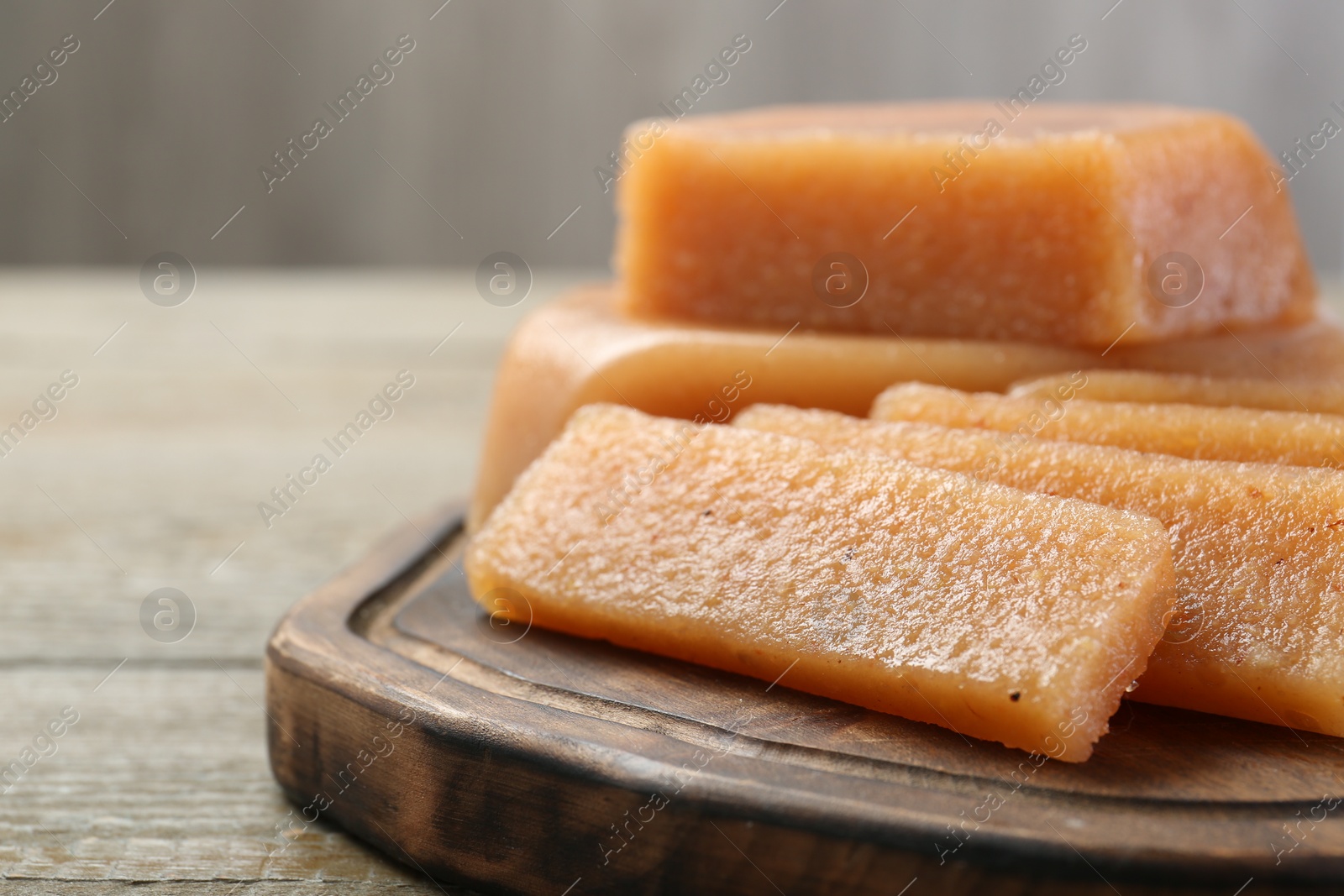 Photo of Tasty sweet quince paste on wooden table, closeup. Space for text