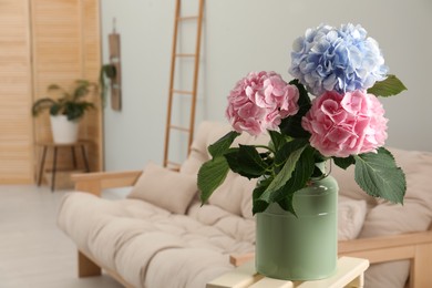Photo of Beautiful hortensia flowers in can on stand indoors. Space for text