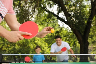 Photo of Family with child playing ping pong in park, closeup