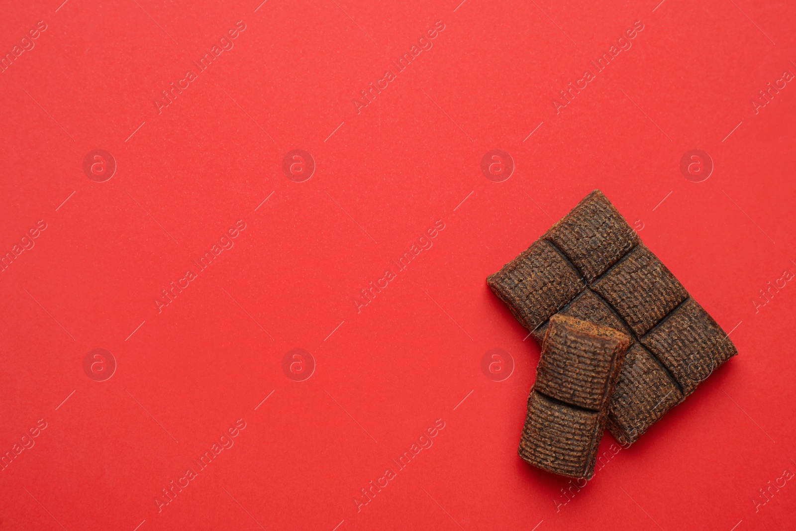 Photo of Pieces of delicious hematogen bar on red background, flat lay. Space for text