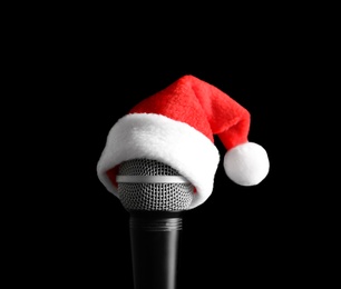 Photo of Microphone with Santa hat on black background. Christmas music concept