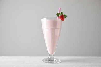 Tasty strawberry milk shake in glass on white wooden table