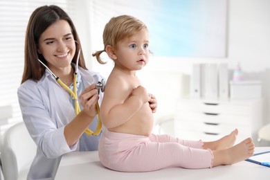 Pediatrician examining baby with stethoscope in clinic