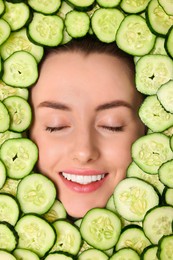 Photo of Beautiful woman among cucumber slices, top view