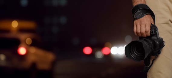 Professional photographer with modern camera and blurred view of night city, space for text. Banner design