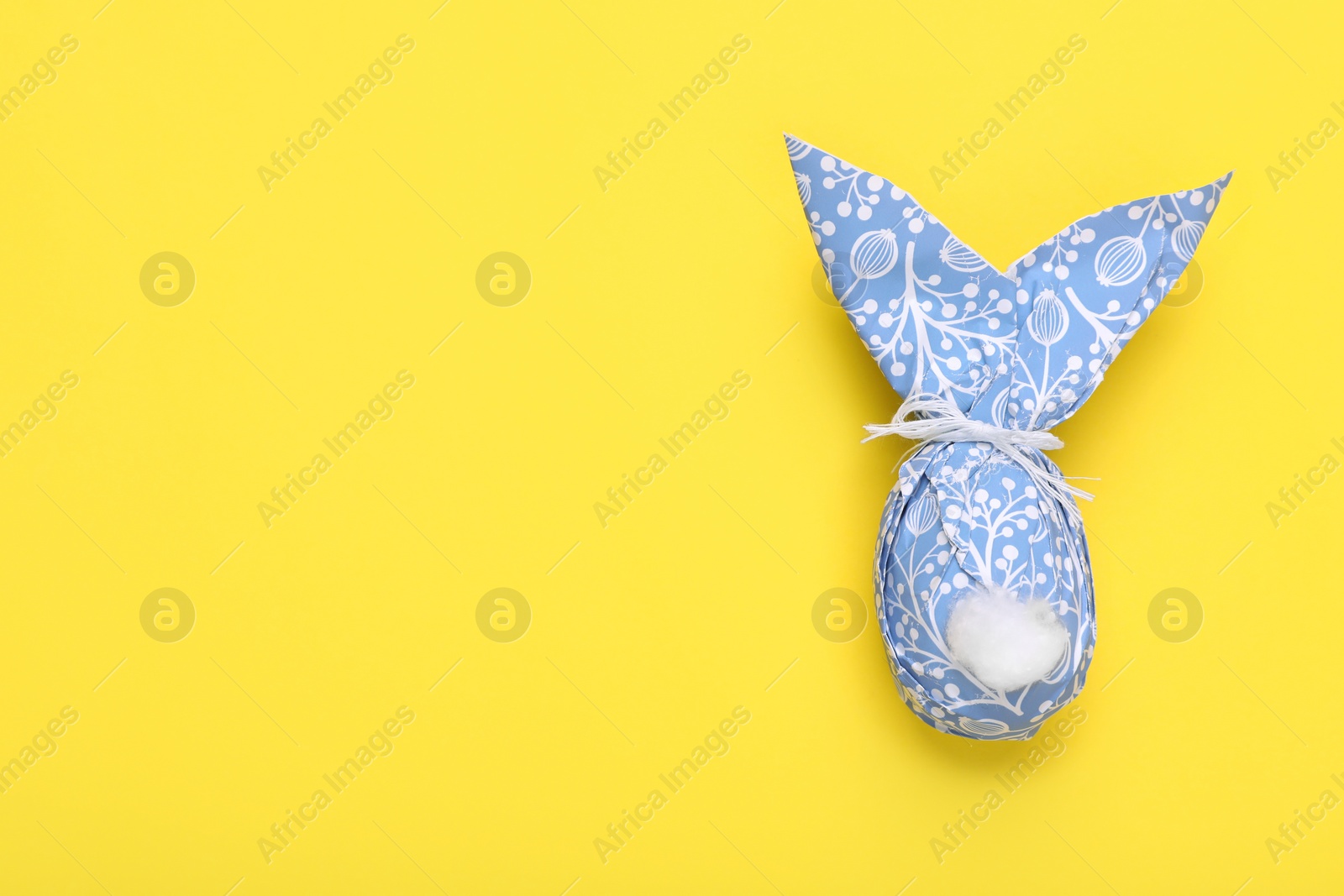 Photo of Easter bunny made of paper with pattern and egg on yellow background, top view. Space for text