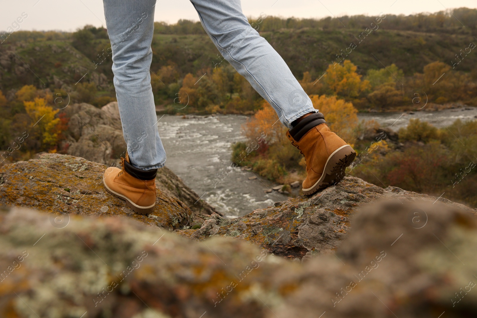 Photo of Man wearing stylish hiking boots on steep cliff, closeup