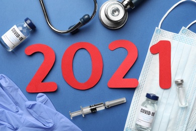 Photo of Flat lay composition with coronavirus vaccine and number 2021 on blue background