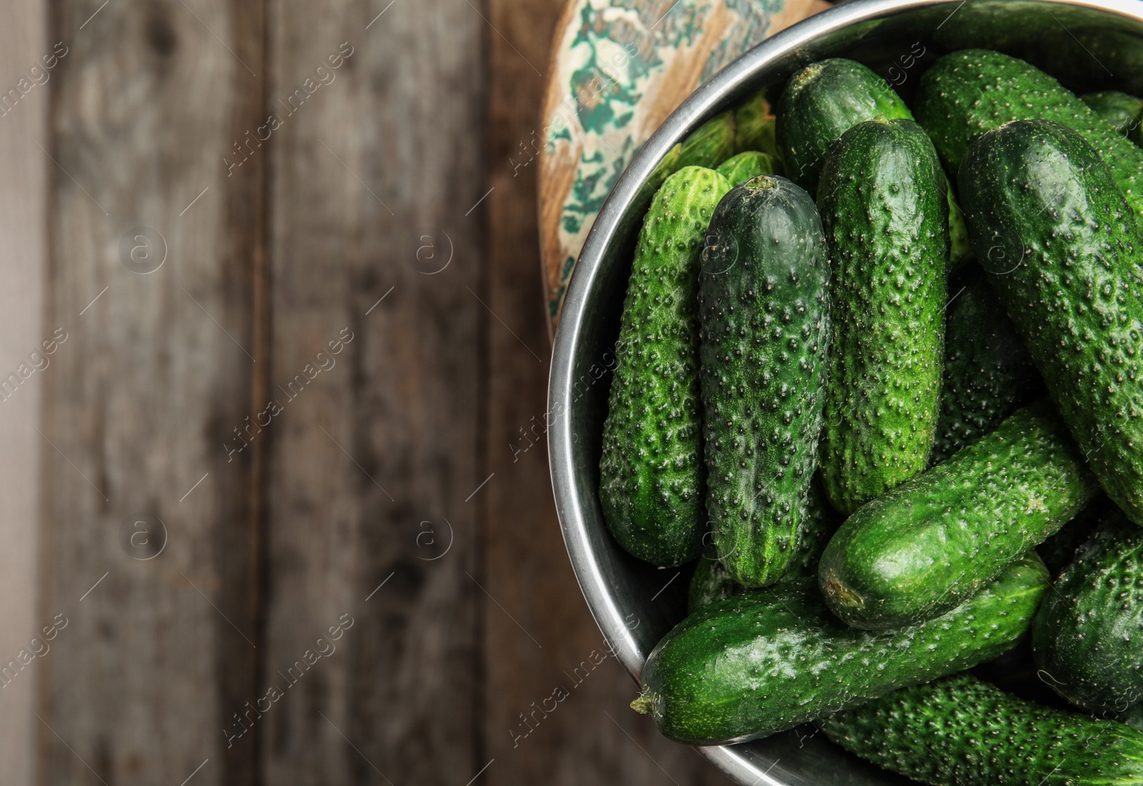 Photo of Bowl with ripe fresh cucumbers on table, top view