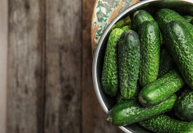 Photo of Bowl with ripe fresh cucumbers on table, top view