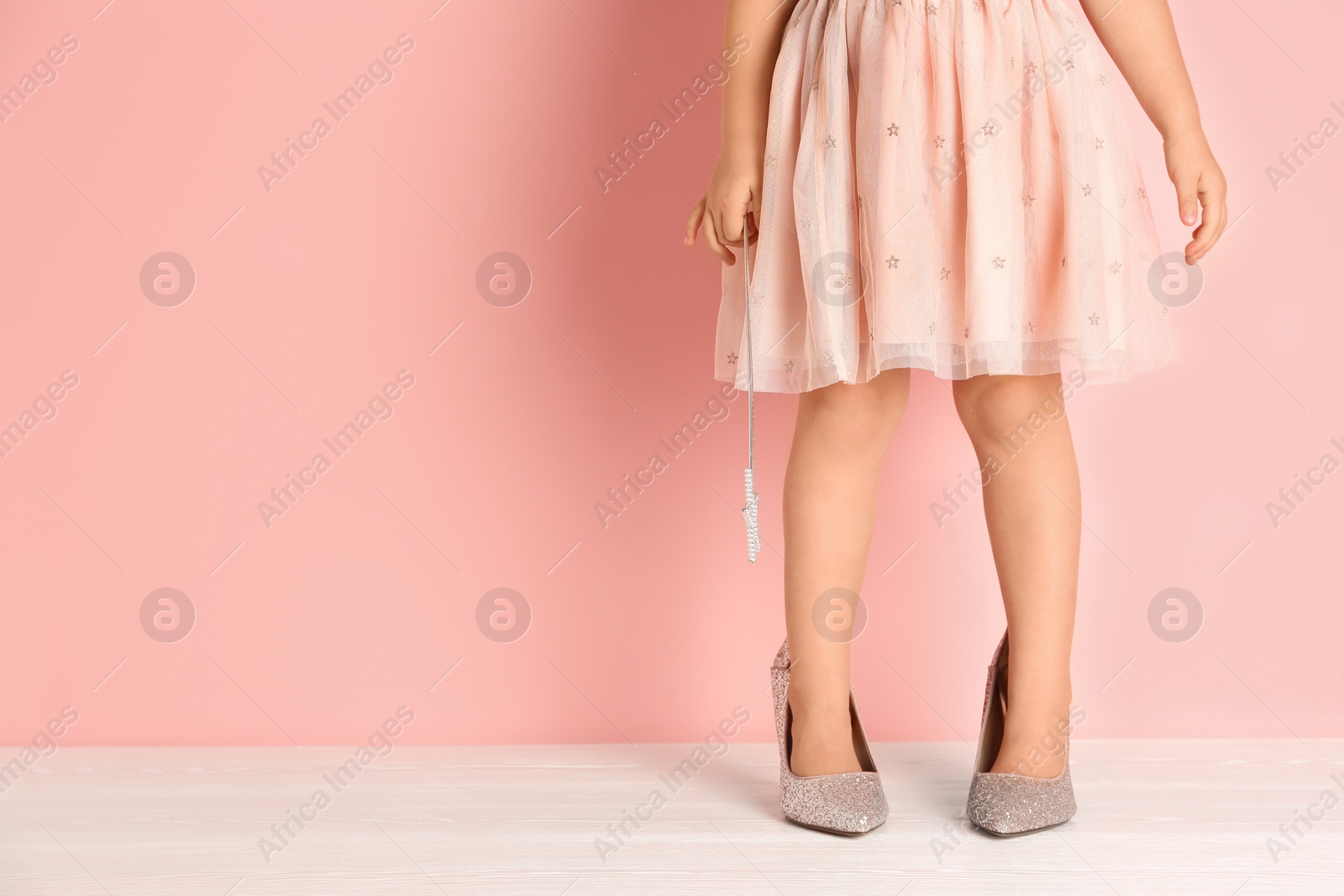 Photo of Little girl in oversized shoes near color wall with space for text, closeup on legs