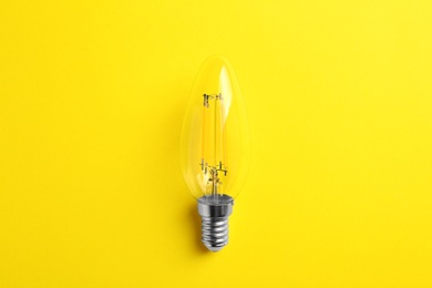 Photo of Vintage filament lamp bulb on yellow background, top view