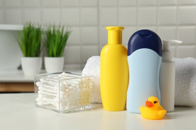 Photo of Baby cosmetic products, bath duck, cotton swabs and towel on white table