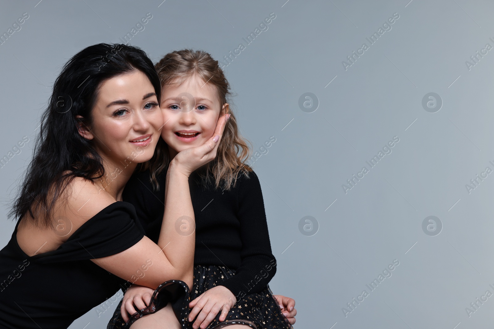 Photo of Beautiful mother with little daughter on grey background. Space for text