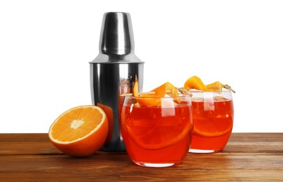 Photo of Aperol spritz cocktail with orange slices in glasses and shaker on wooden table against white background