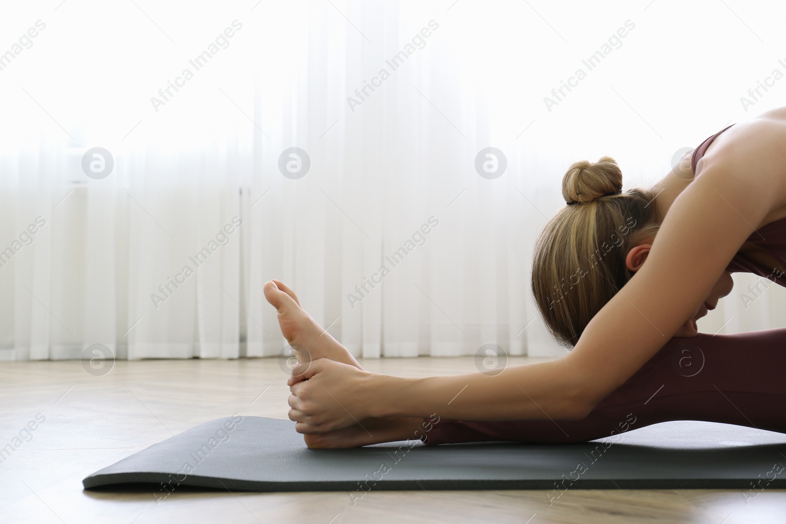 Photo of Young woman practicing head to knee asana in yoga studio. Janu Sirsasana pose