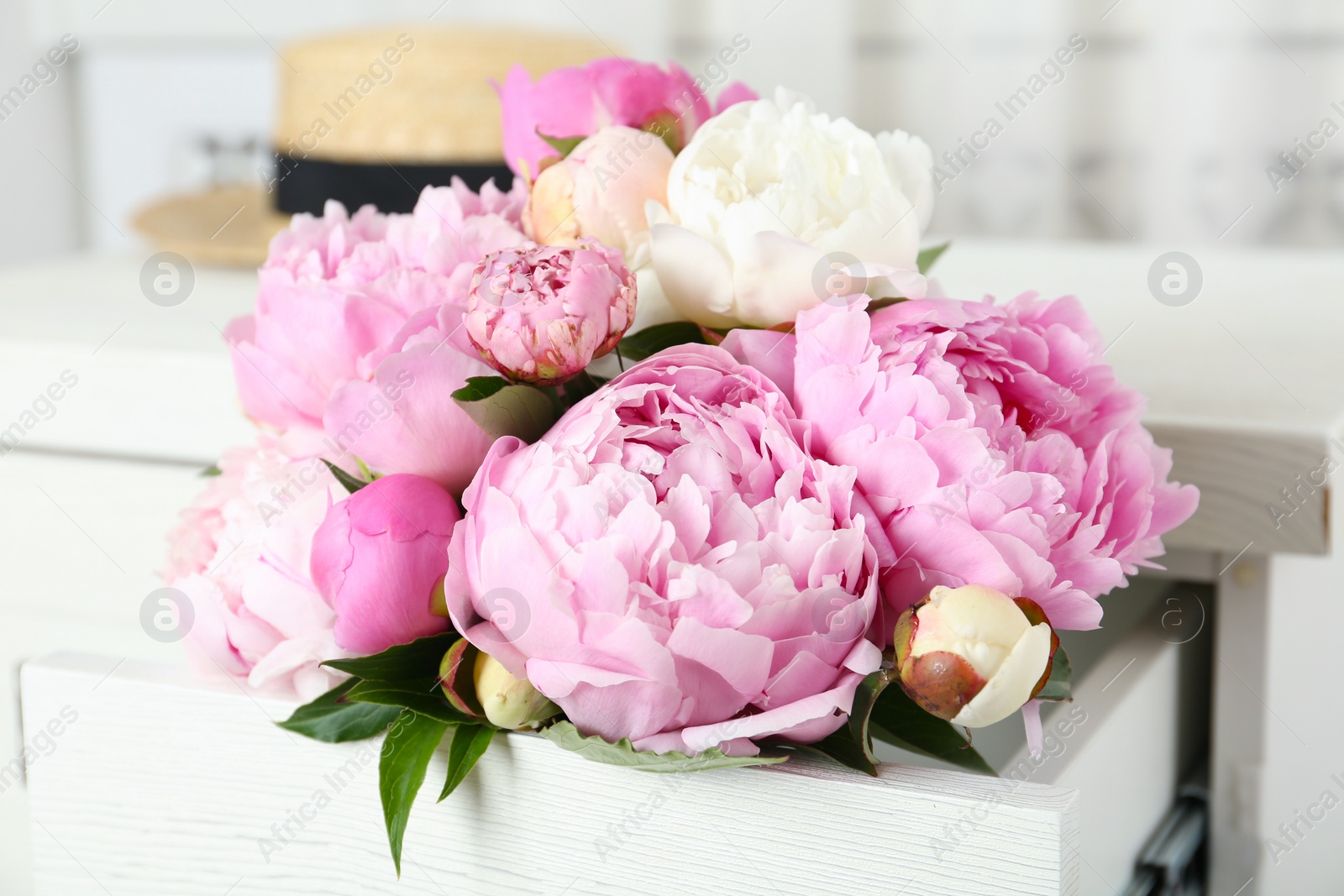 Photo of Bouquet of beautiful peonies in commode drawer indoors