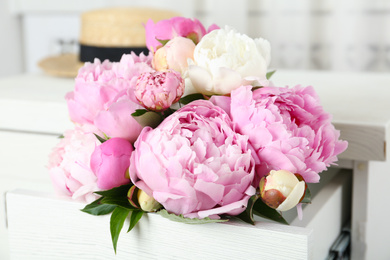 Bouquet of beautiful peonies in commode drawer indoors