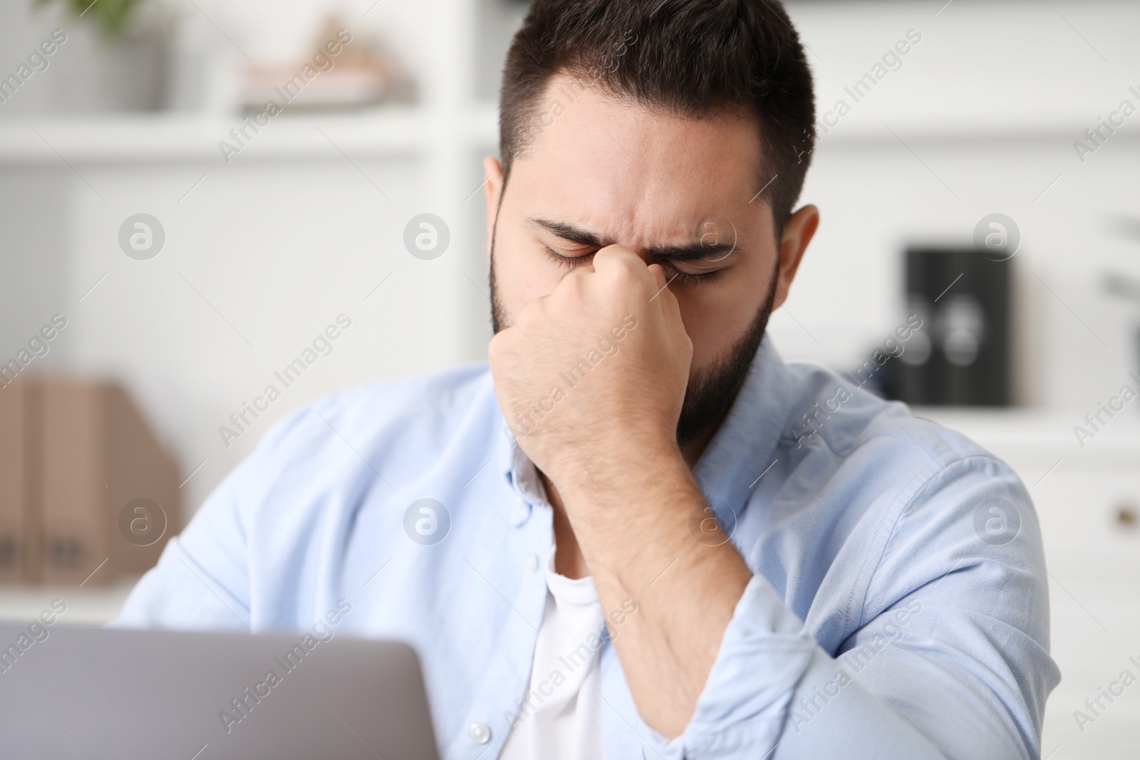 Photo of Man suffering from headache at workplace in office