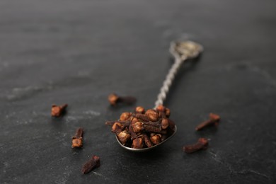 Aromatic dry cloves with spoon on black table