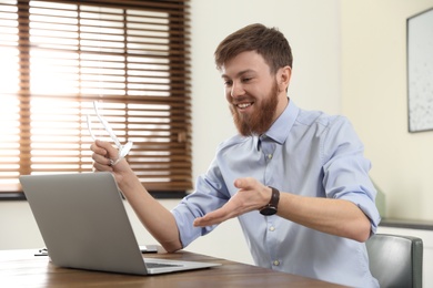 Photo of Man using video chat on laptop in home office