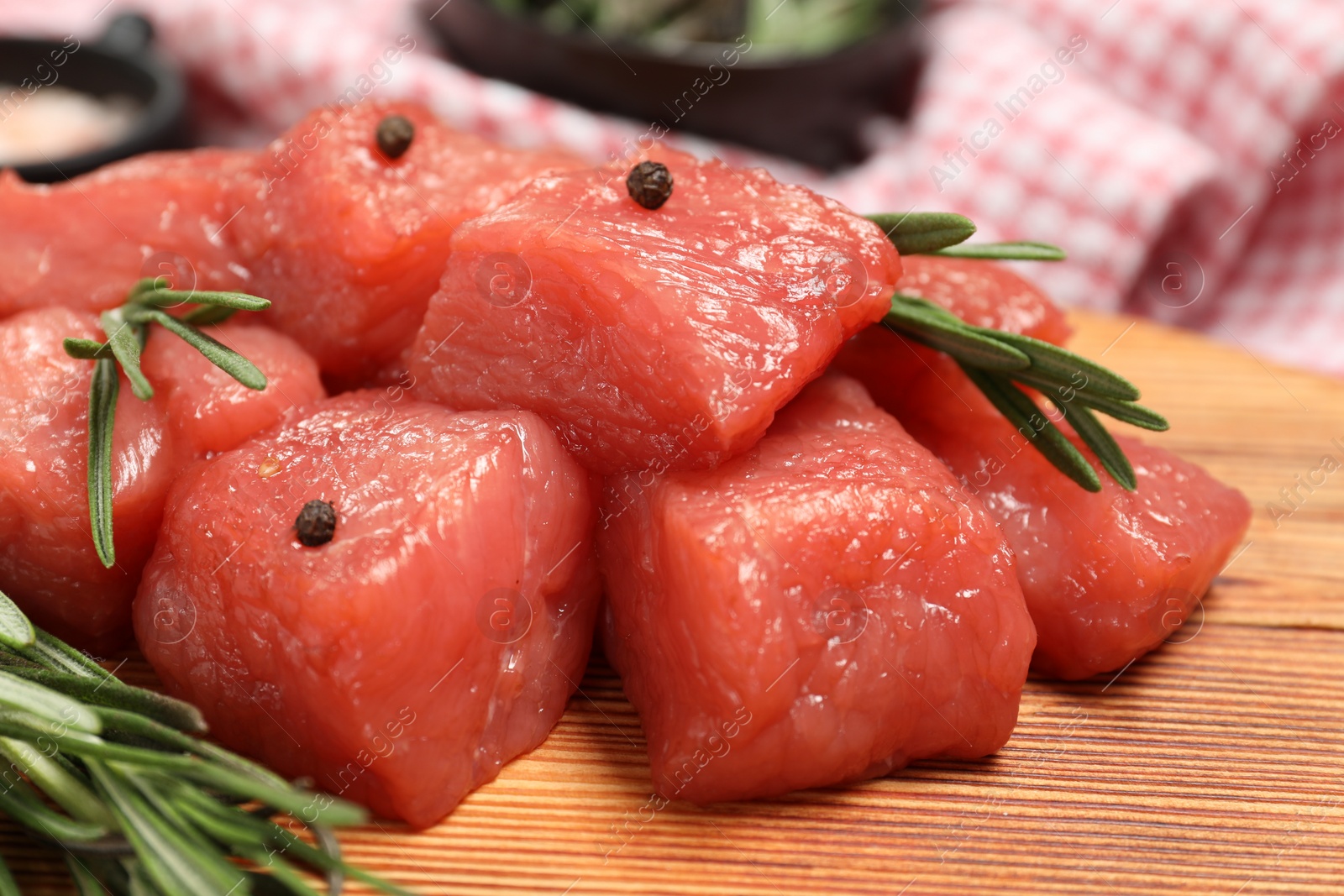 Photo of Cooking delicious goulash. Raw beef meat with rosemary on wooden table, closeup