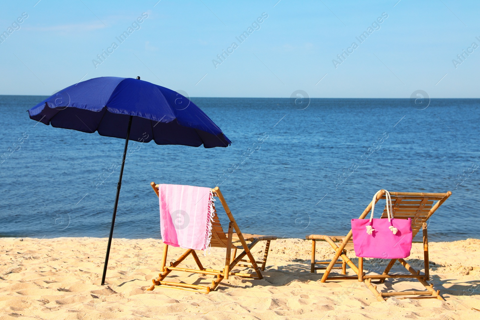 Photo of Empty wooden sunbeds and beach accessories on sandy shore