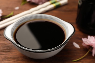 Bowl with soy sauce on wooden table, closeup