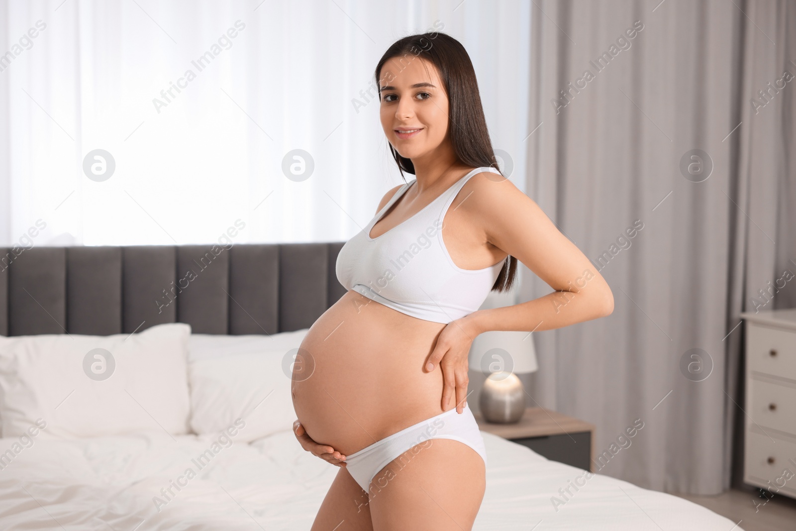 Photo of Beautiful pregnant woman wearing stylish comfortable underwear in bedroom