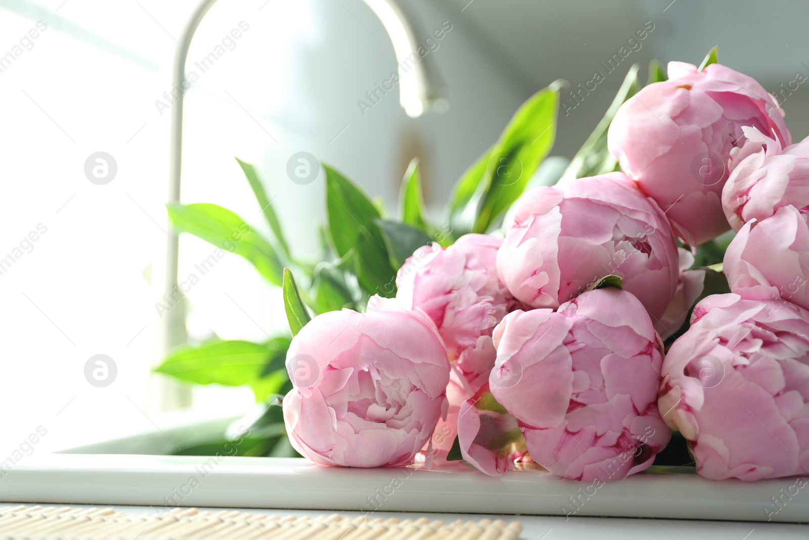 Photo of Bouquet of beautiful pink peonies in kitchen sink