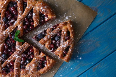 Photo of Delicious cut currant pie and fresh berries on blue wooden table, flat lay