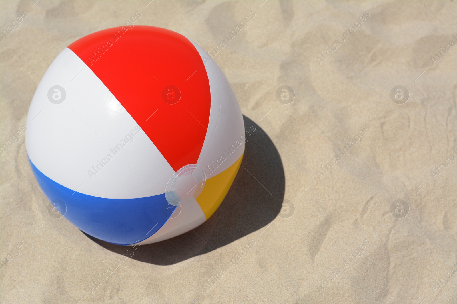 Photo of Colorful beach ball on sand, space for text