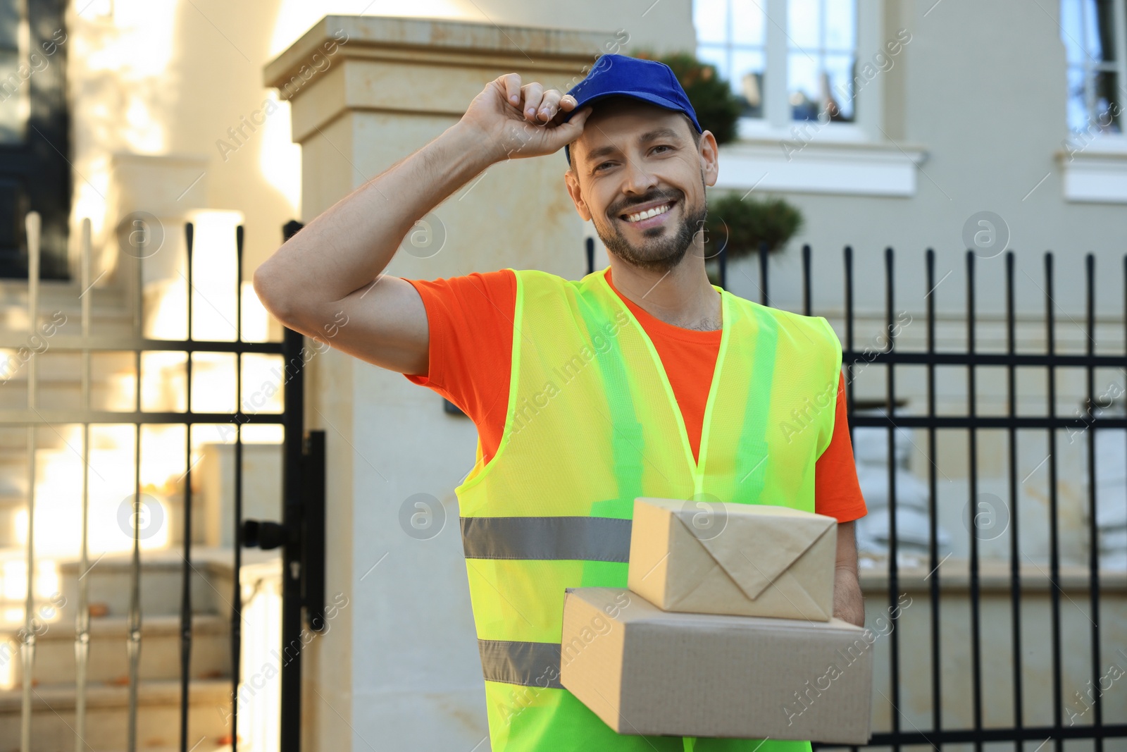 Photo of Courier in uniform with two parcels outdoors