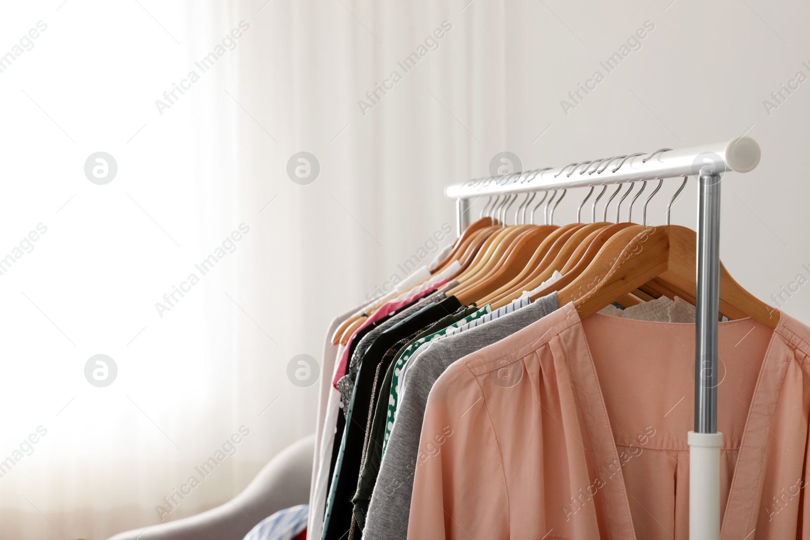 Photo of Wardrobe rack with stylish clothes indoors. Space for text