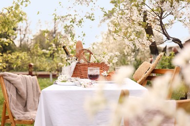 Photo of Stylish table setting with beautiful spring flowers, wine and croissants in garden