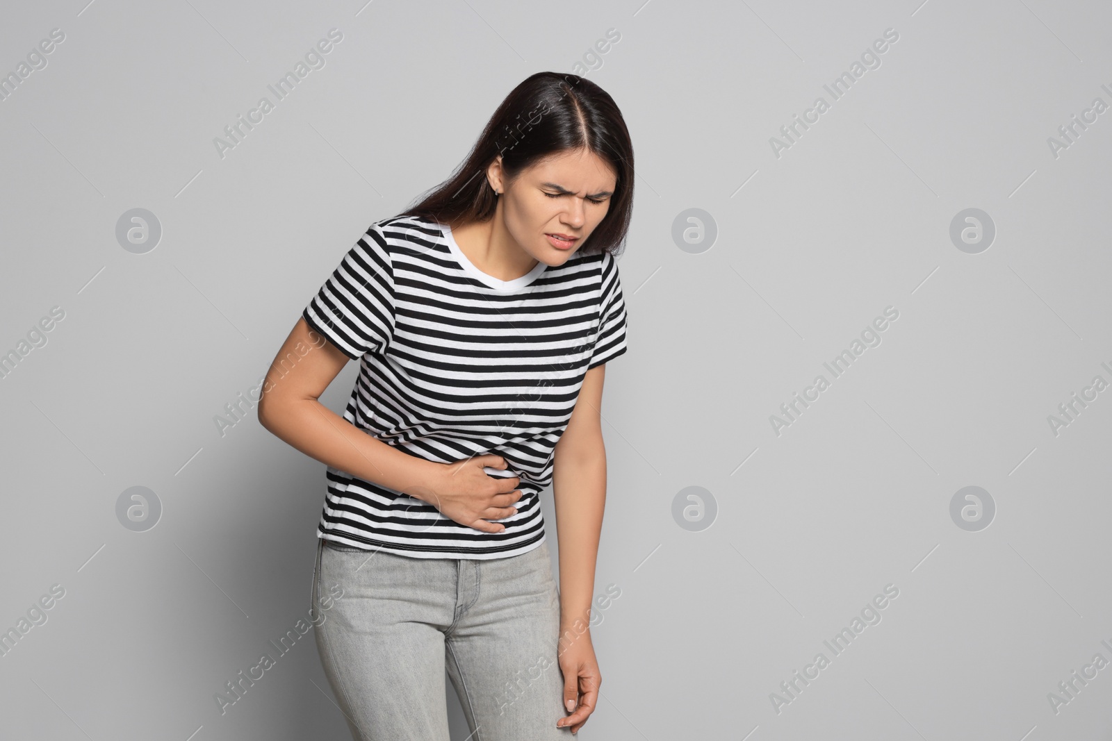 Photo of Young woman suffering from menstrual pain on grey background, space for text