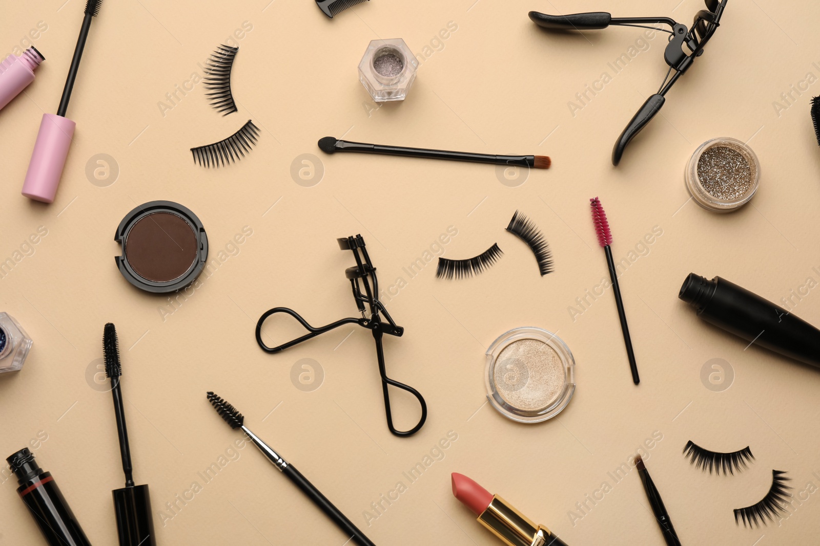 Photo of Flat lay composition with eyelash curlers, makeup products and accessories on beige background